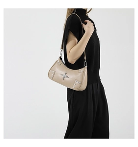 Détail d'un sac hobo beige avec étoile argentée et rivets sur une tenue noire