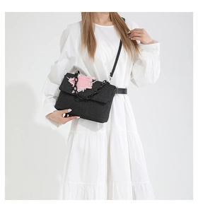 Detail van zwarte denim crossbodytas met roze gerafelde ster en zilverkleurige ketting