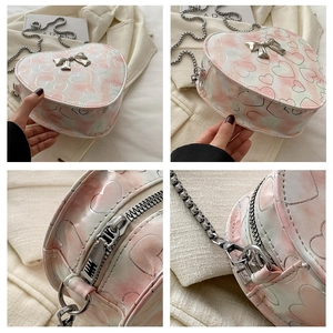Detail of heart-shaped crossbody bag featuring marble texture and metal bow ornament