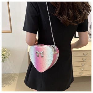 Détail du sac bandoulière en forme de cœur avec dégradé iridescent et nœud argenté