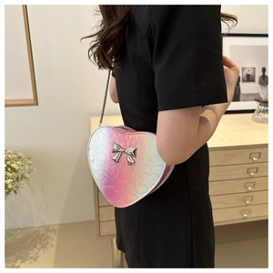 Détail du sac à bandoulière en forme de cœur dégradé rose avec nœud argenté et chaîne