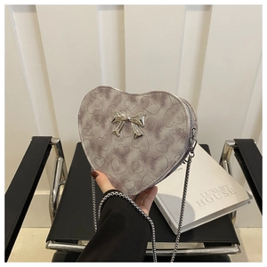 Detail of light purple heart-shaped bag with silver bow accent and metal chain strap