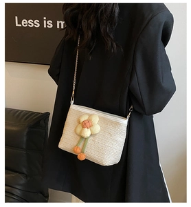 Dettaglio mini borsa a tracolla in paglia con decori floreali e catena d'oro