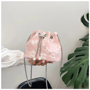 Detail of pink drawstring bucket bag featuring white floral patterns and pearl charms