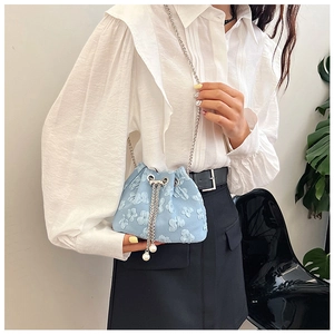 Detail of light blue bucket bag with floral embroidery, chain strap and pearl charms