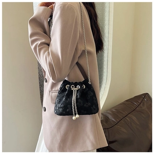 Detail of black floral bucket bag with silver chain strap and pearl drawstring tassels