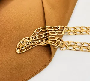 Gros plan sur la bandoulière en chaîne dorée brillante du sac en dentelle de paille