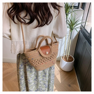 Détail du sac en paille tressée avec rabat en cuir, fermoir perle et accents colorés