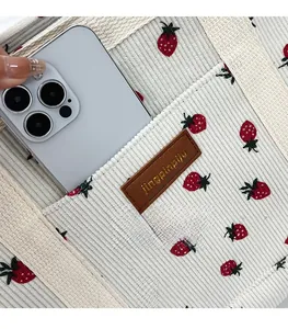 Detail of corduroy tote bag showing front pocket storage with strawberry pattern