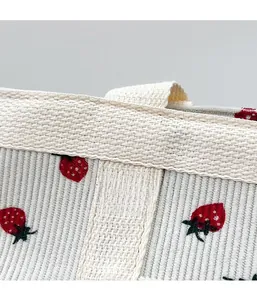 Detail of corduroy fabric featuring strawberry embroidery and woven handles