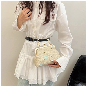 Dettaglio borsa in paglia beige con ricami floreali blu e manico ad anello dorato