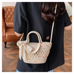 Détail du sac cabas tissé main avec broderies colorées et grand nœud en dentelle