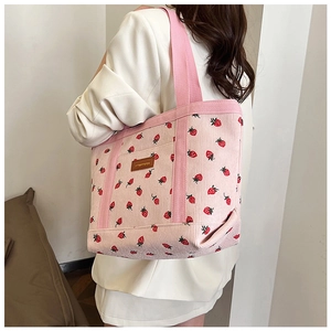 Detail of pink corduroy tote bag with red strawberry print and branded leather patch