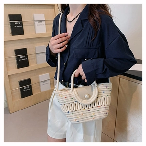Détail du sac de plage tissé montrant des accents colorés, boucle perle et texture