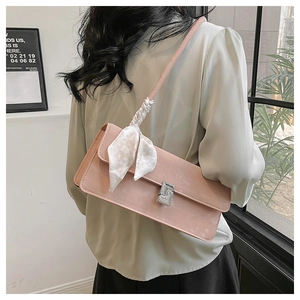 Détail du sac à bandoulière rose en cuir avec boucle argentée et foulard en soie