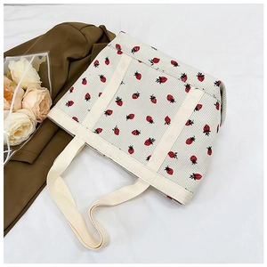 Close-up of cream corduroy tote bag with red strawberry print and wide handles