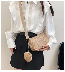 Detail of beige woven crossbody bag with a round coin purse and wide fabric strap