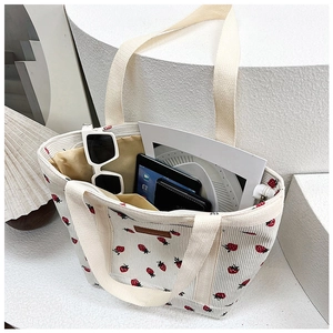 Detail of canvas tote bag with strawberry embroidery showing spacious interior and items