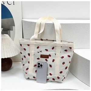 Detail of corduroy tote bag with red strawberry print next to smartphone for scale