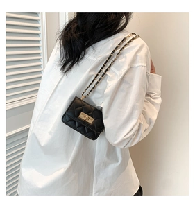 Dettaglio della mini borsa trapuntata nera con chiusura a rotazione dorata e tracolla a catena