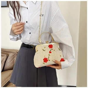Détail du sac en paille avec broderie florale rouge et fermoir vintage en métal doré