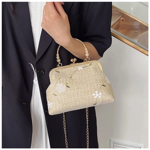 Dettaglio borsa in pizzo intrecciato beige con ricamo floreale e chiusura in metallo oro