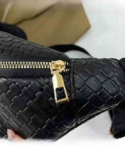 Dettaglio macro della cerniera in metallo dorato e della trama intrecciata nera della borsa