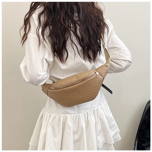 Dettaglio di una borsa a tracolla intrecciata color cuoio con cerniera dorata