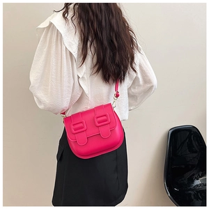 Détail d'un sac bandoulière fuchsia vif avec doubles boucles sur fond minimaliste