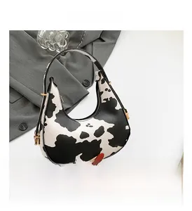 Macro detail of cow print crescent bag with golden metal zipper and hardware accents