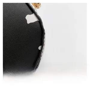 Macro shot of black and white cow print leather bag with fine stitching and golden zipper
