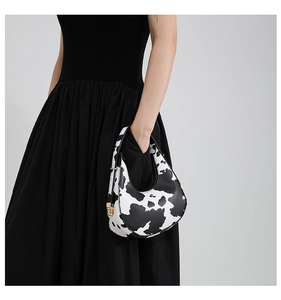 Close-up of black and white cow print hobo bag with elegant gold metal buckle detail