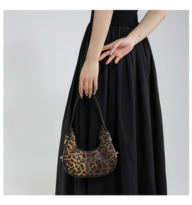 Close-up of leopard print hobo bag with gold metal buckle detail and slim shoulder strap