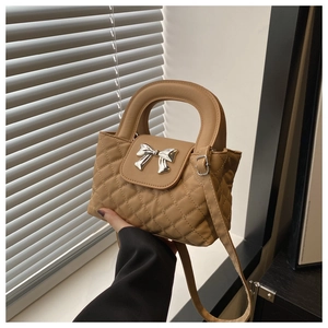 Detail van beige gewatteerde tas met zilveren strik en ronde handgreep design