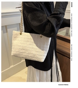 Close-up of white woven tweed tote bag featuring luxury texture and gold chain strap