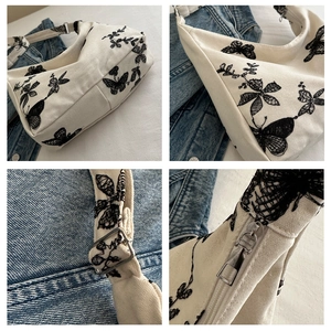 Detail of floral butterfly embroidery on white canvas shoulder bag with metal buckle