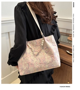 Detail of jacquard tote bag featuring pearl chain ornament and woven texture