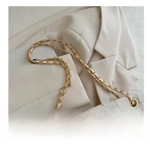 Detail of woven chain strap with gold hardware on white textured fabric tote bag