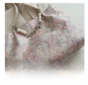 Detail of jacquard fabric handbag featuring a faux pearl and hollow metal flower chain