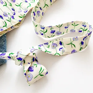 Detail of canvas bag knot shoulder strap featuring purple pansy floral print texture