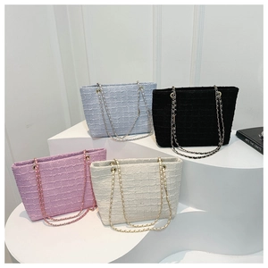 Group of textured tweed tote bags in blue, black, purple, and cream on geometric stands