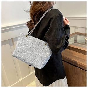Detail der hellblauen Tweed-Einkaufstasche mit Webstruktur und Metallkettenriemen am Modell
