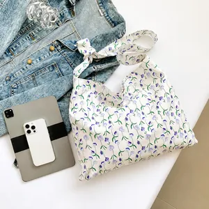 Detail of floral canvas tote bag showing large capacity next to a tablet and jacket