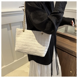 Detail of white tweed texture on shoulder bag with elegant double gold chain straps