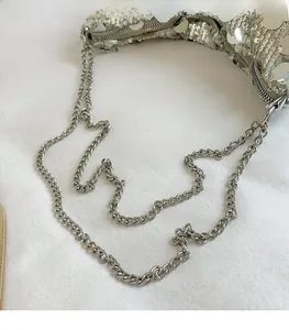 Detail shot of silver sequin surface and polished metal chain strap of the crossbody bag