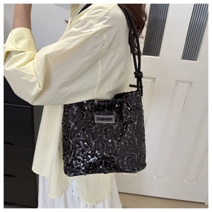 Detail einer schwarzen Pailletten-Beuteltasche mit Fashion-Patch und Knotengurt