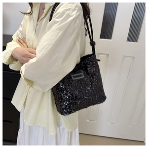 Detail der schwarzen Pailletten-Tasche mit FASHION-Label und geknotetem Riemen