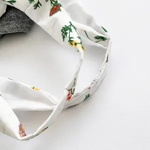 Dettaglio del comodo spallaccio largo con motivi floreali su una borsa tote in tela