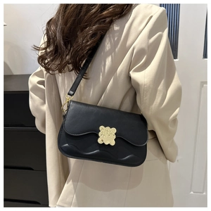 Modèle portant un sac bandoulière noir avec boucle nuage dorée et texture ondulée