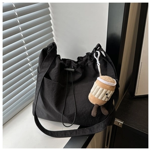 Close-up of black nylon tote bag with drawstring detail and cute coffee plush keychain